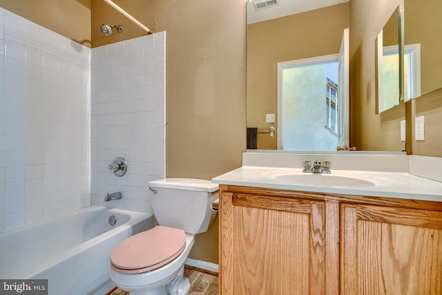 full bathroom featuring tiled shower / bath, vanity, and toilet