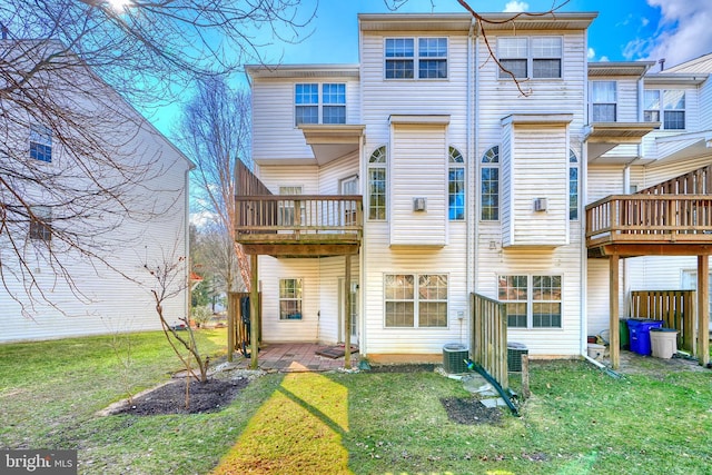 rear view of house featuring central AC unit and a lawn