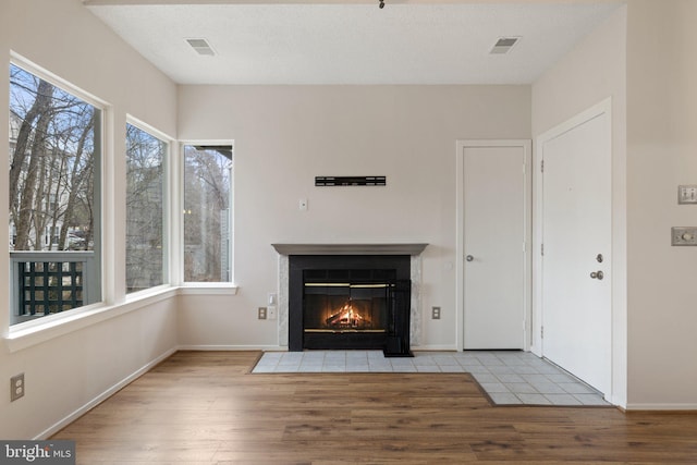 unfurnished living room with a textured ceiling and light hardwood / wood-style flooring