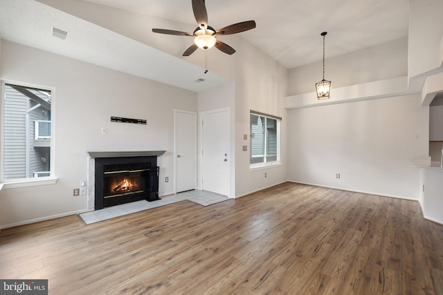 unfurnished living room with wood-type flooring, a towering ceiling, and ceiling fan