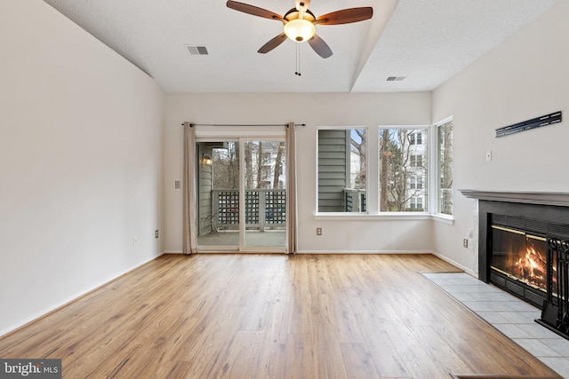 unfurnished living room with ceiling fan, a textured ceiling, and light wood-type flooring