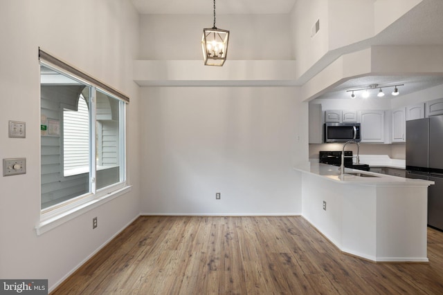 kitchen featuring pendant lighting, sink, stainless steel appliances, white cabinets, and kitchen peninsula