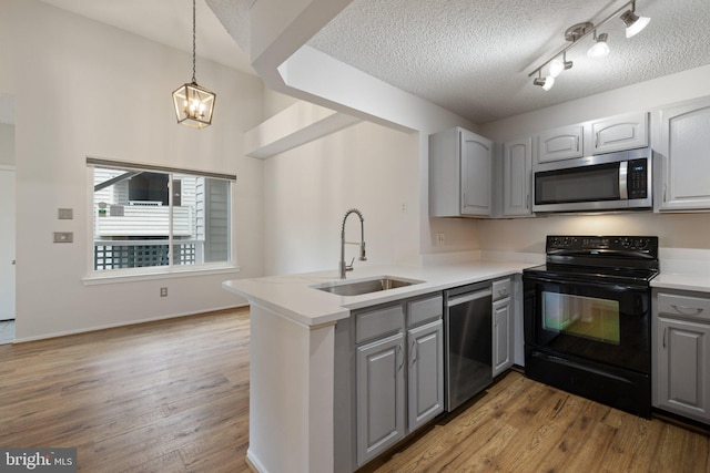 kitchen with sink, gray cabinetry, stainless steel appliances, light hardwood / wood-style floors, and kitchen peninsula