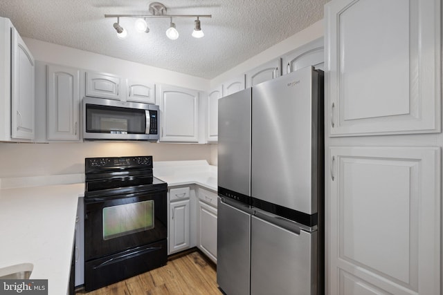 kitchen with white cabinetry, stainless steel appliances, light hardwood / wood-style floors, and a textured ceiling