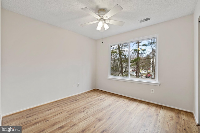 empty room with a textured ceiling, light hardwood / wood-style floors, and ceiling fan