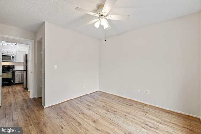 unfurnished room with ceiling fan, light hardwood / wood-style floors, and a textured ceiling