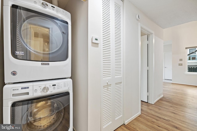 clothes washing area with stacked washer / drying machine and light hardwood / wood-style floors