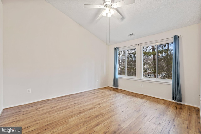 empty room featuring ceiling fan, vaulted ceiling, light hardwood / wood-style floors, and a textured ceiling