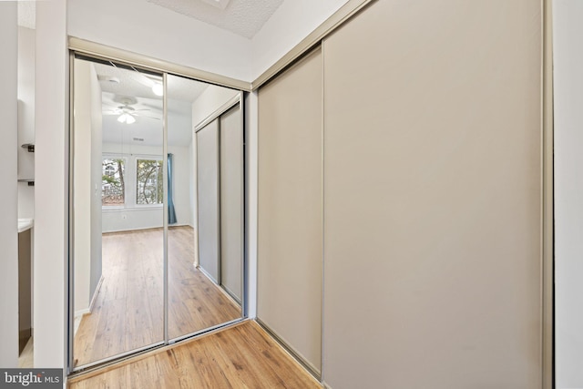 hallway with a textured ceiling and light wood-type flooring