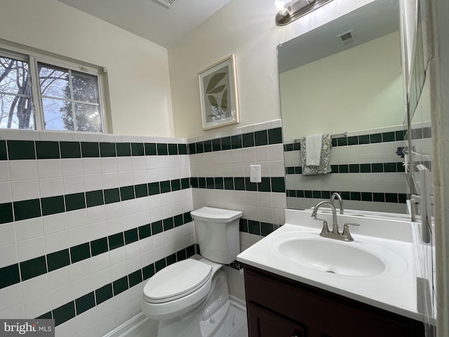 bathroom with toilet, tile walls, and vanity