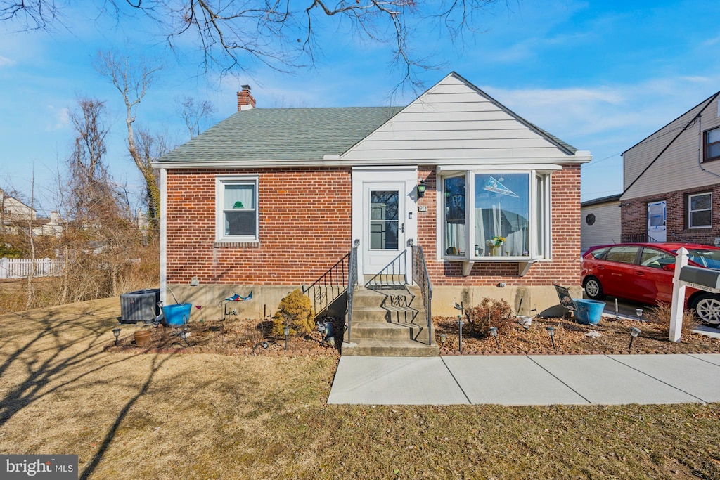 bungalow featuring central AC unit and a front lawn