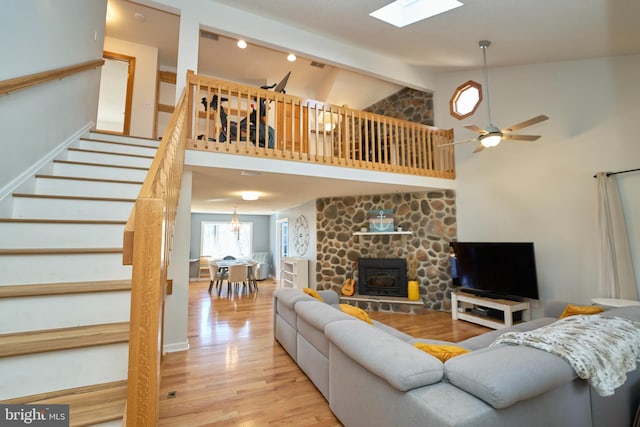 living area with high vaulted ceiling, a ceiling fan, light wood-style floors, stairway, and beamed ceiling