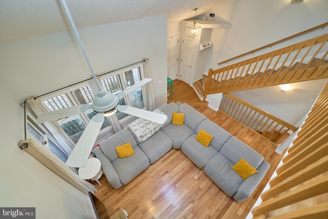 living area featuring a textured ceiling, lofted ceiling, wood finished floors, baseboards, and stairs