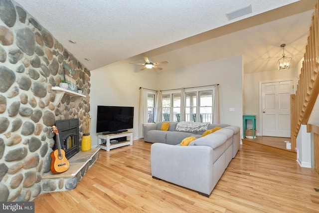 living room featuring light wood-style flooring, visible vents, vaulted ceiling, and a textured ceiling