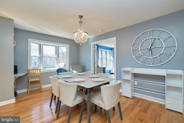 dining space with a chandelier, light wood-type flooring, a healthy amount of sunlight, and baseboards