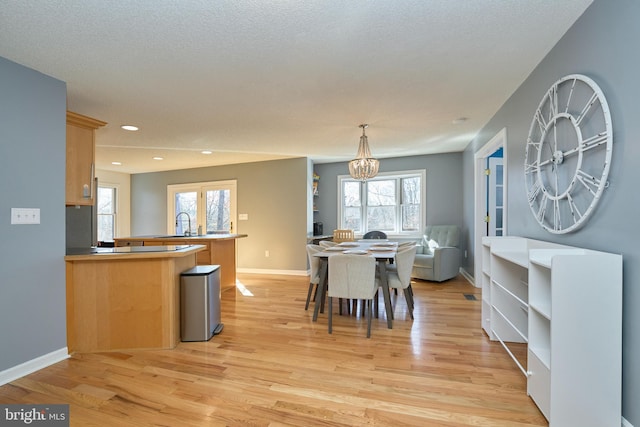 dining area with light wood-type flooring, baseboards, a notable chandelier, and recessed lighting