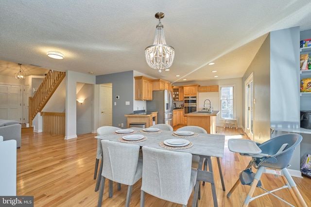 dining area with light wood finished floors, a textured ceiling, stairway, and a notable chandelier