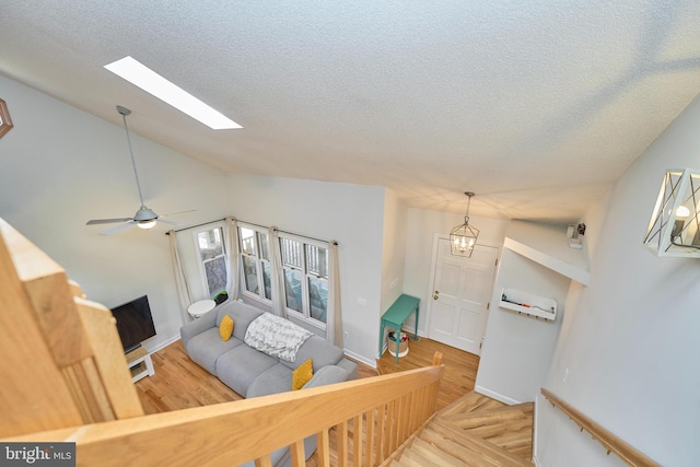 living area with a textured ceiling, vaulted ceiling with skylight, and wood finished floors