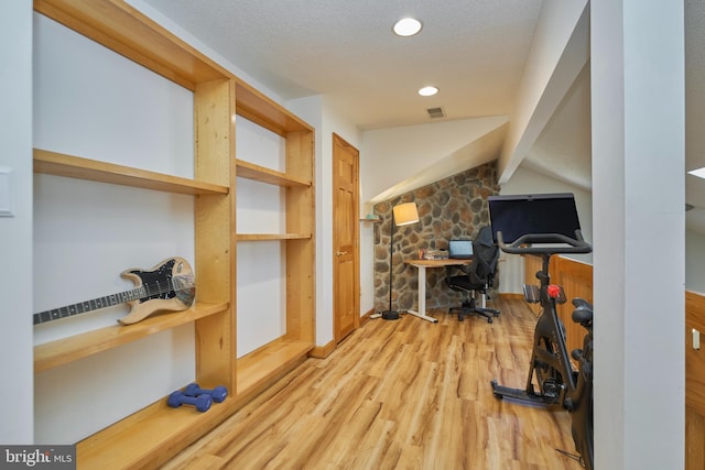 workout area featuring visible vents, wood finished floors, vaulted ceiling, a textured ceiling, and recessed lighting