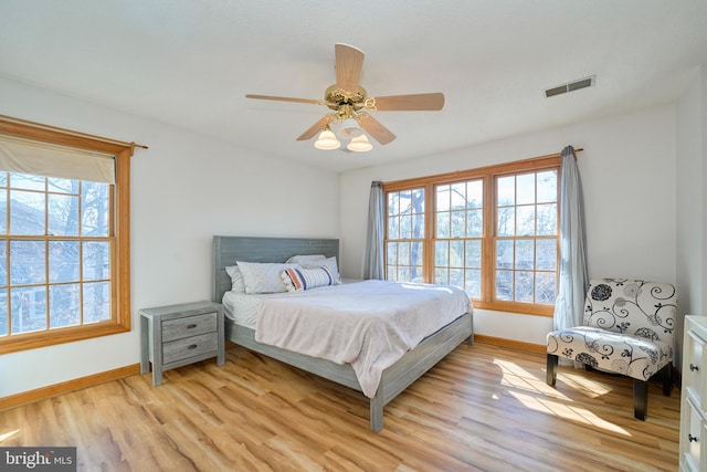 bedroom with light wood-style floors, baseboards, visible vents, and a ceiling fan