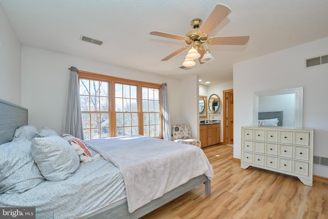 bedroom featuring light wood-style flooring, visible vents, a ceiling fan, and ensuite bathroom