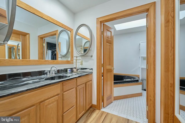 bathroom with a skylight, vanity, and wood finished floors