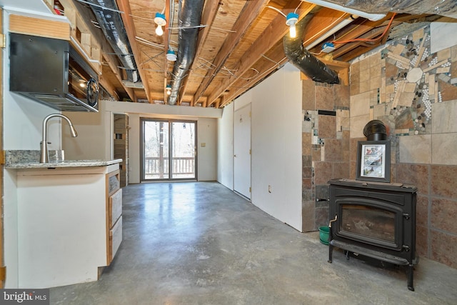 interior space featuring a sink, a wood stove, and concrete flooring