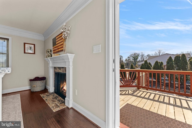 interior space featuring baseboards, hardwood / wood-style floors, a fireplace, and crown molding