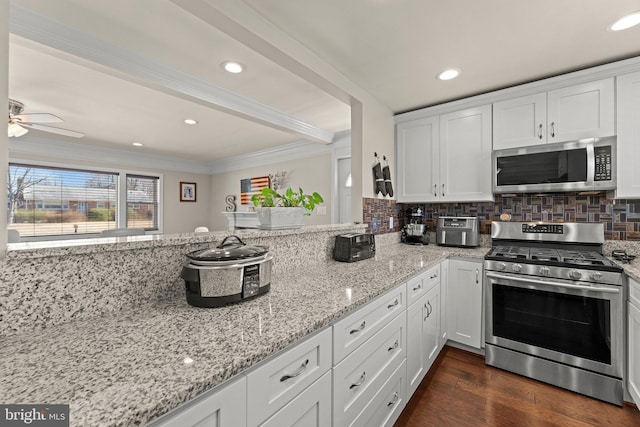 kitchen with appliances with stainless steel finishes, dark wood-style flooring, white cabinetry, and backsplash