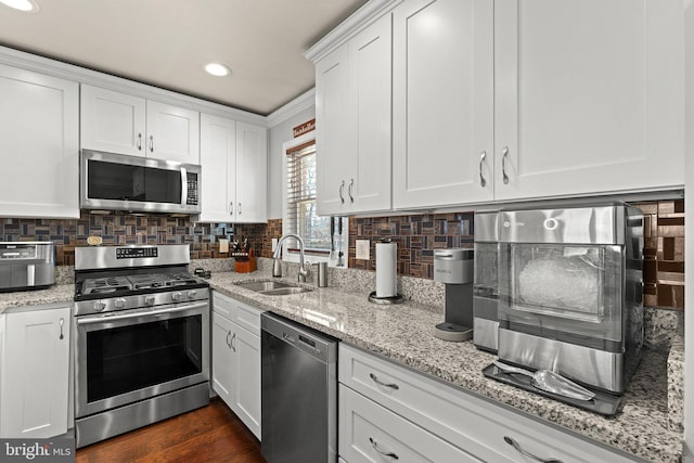 kitchen with stainless steel appliances, white cabinetry, a sink, and tasteful backsplash