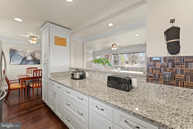 kitchen with dark wood-style floors, white cabinetry, light stone countertops, and crown molding