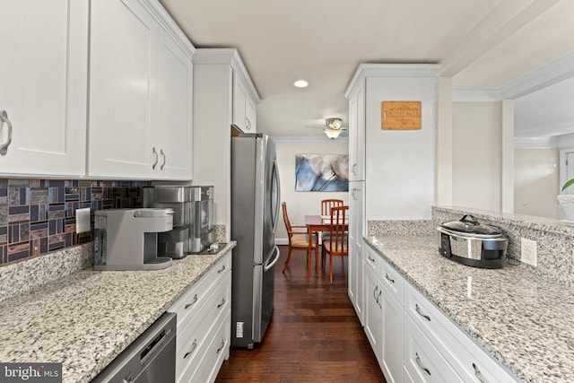 kitchen with dark wood-style floors, appliances with stainless steel finishes, white cabinets, and backsplash