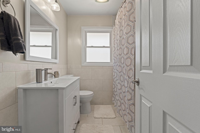 full bath featuring wainscoting, toilet, tile patterned flooring, vanity, and tile walls