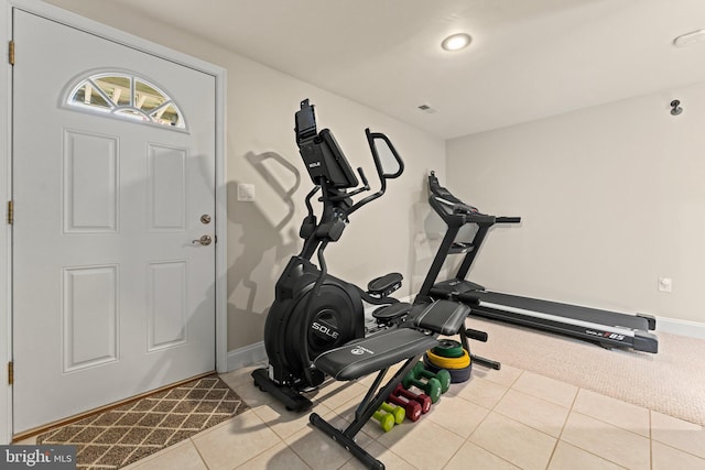 exercise area with carpet, tile patterned flooring, and baseboards