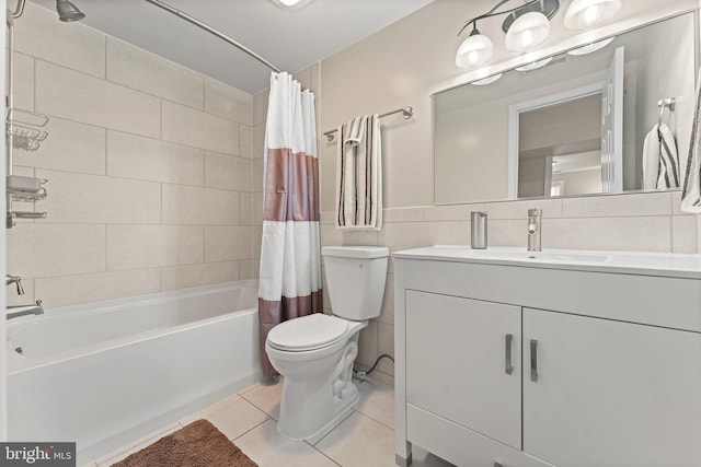 bathroom with toilet, tile patterned floors, shower / bath combination with curtain, vanity, and tile walls