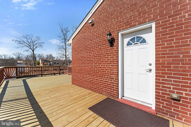 entrance to property featuring a deck and brick siding