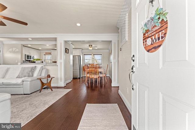 entrance foyer with baseboards, dark wood finished floors, a ceiling fan, and crown molding