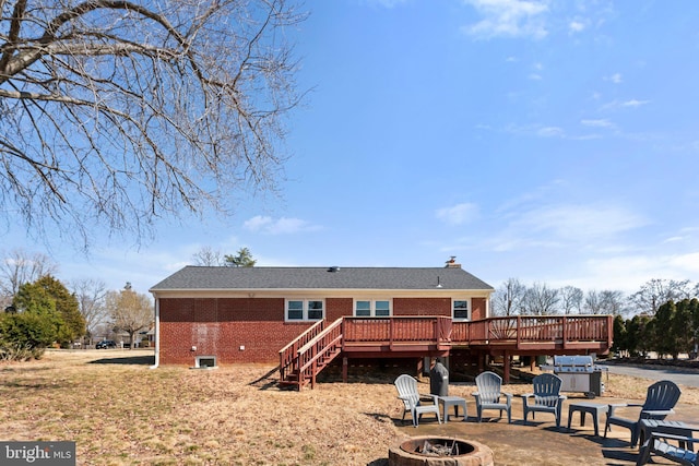 back of property featuring brick siding, a chimney, stairway, a fire pit, and a wooden deck