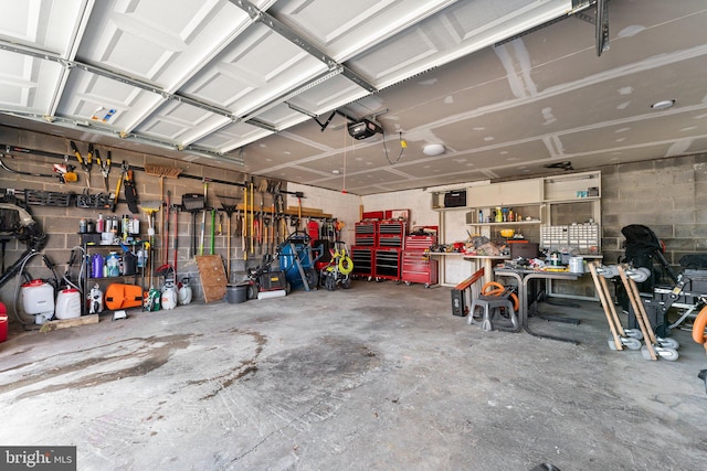 garage featuring concrete block wall, a workshop area, and a garage door opener