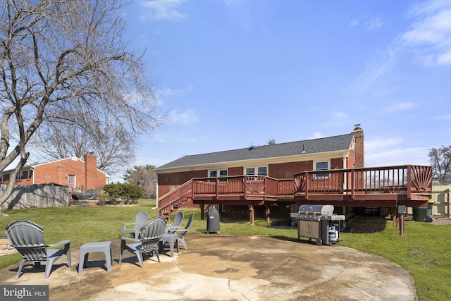 back of house with brick siding, a chimney, a lawn, a patio area, and a wooden deck