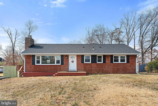 ranch-style home with a front yard, a chimney, fence, and brick siding