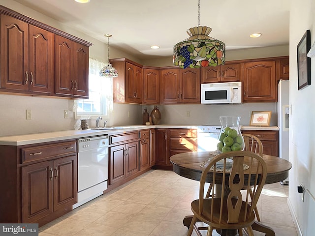 kitchen featuring hanging light fixtures, white appliances, and sink