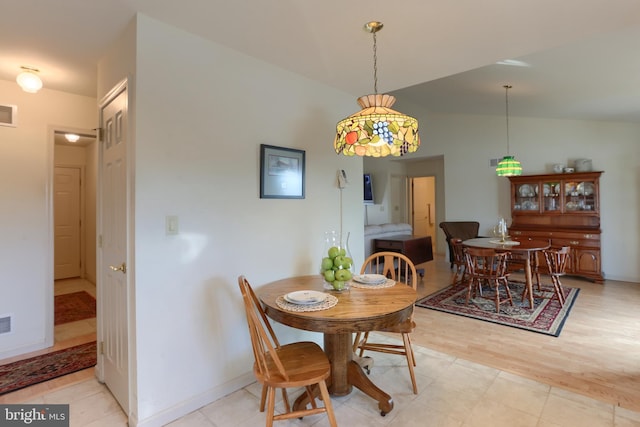 dining space featuring vaulted ceiling and light hardwood / wood-style flooring