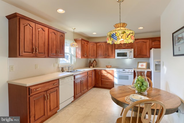 kitchen featuring sink, white appliances, and decorative light fixtures