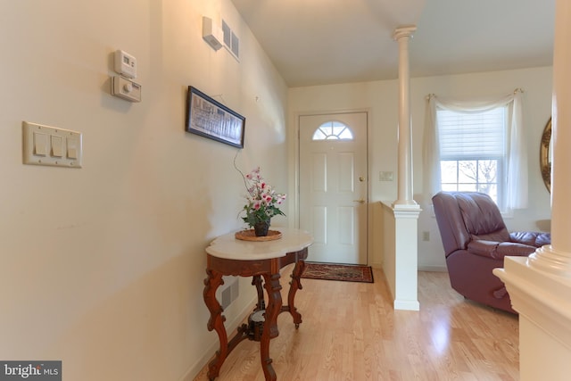 entryway with decorative columns and light hardwood / wood-style flooring