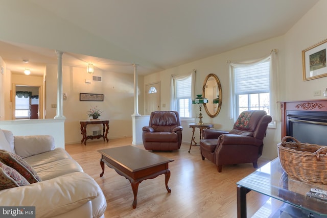 living room featuring light hardwood / wood-style flooring, vaulted ceiling, and ornate columns