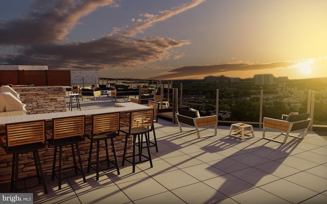 patio terrace at dusk featuring a bar and grilling area