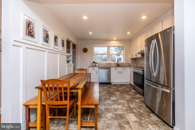 kitchen with backsplash, stainless steel appliances, sink, and white cabinets