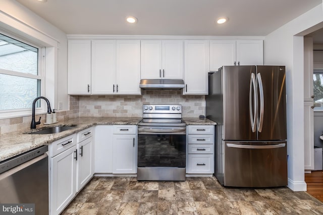 kitchen with tasteful backsplash, white cabinetry, sink, light stone counters, and stainless steel appliances