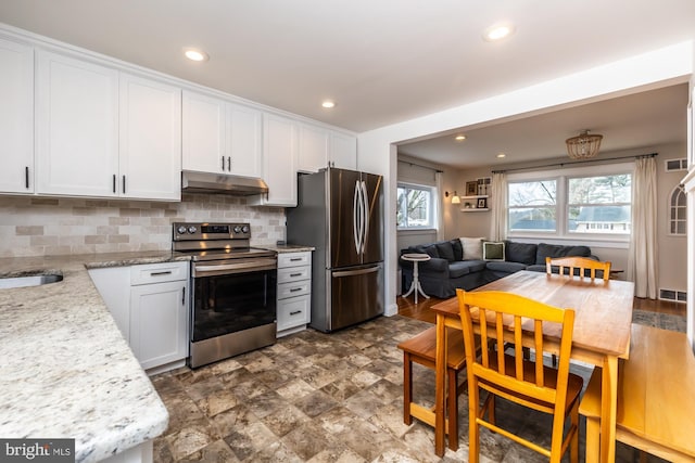 kitchen with tasteful backsplash, stainless steel appliances, light stone countertops, and white cabinets